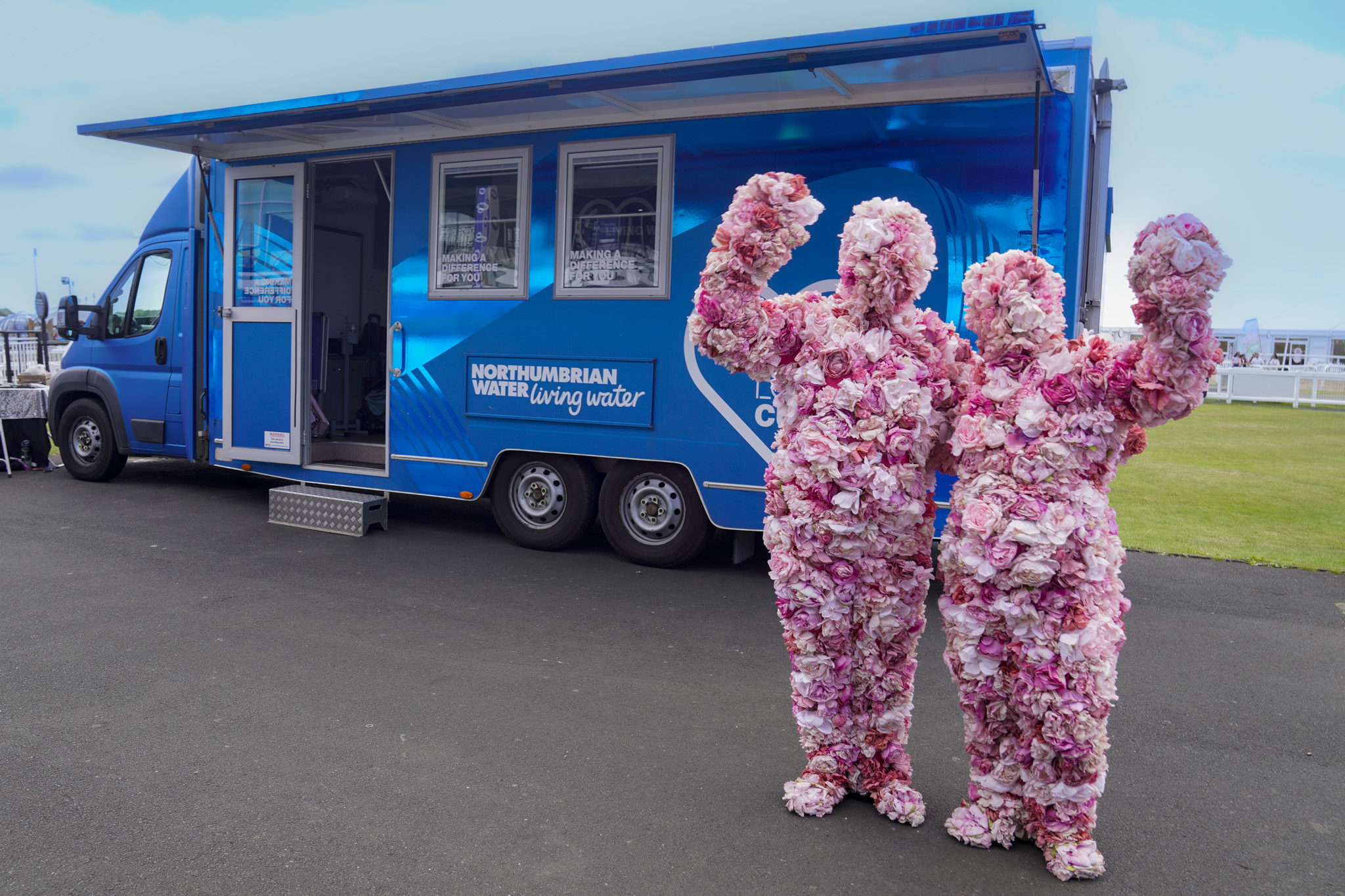 Innovation Festival 2026 - ATMOS - two people in full body flower costumes outside of Flo the NWL customer engagament vehicle